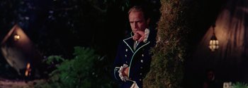 Movie still from “Mutiny on the Bounty” (1962), directed by George Seaton – A man in a suit leaning against a tree; Medium shot, Low angle