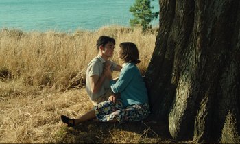 Movie still from “My American Uncle” (1980), directed by Alain Resnais – Two people sitting next to each other near a tree; Medium shot, High angle