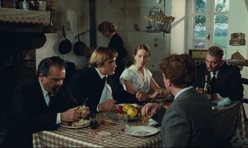 Movie still from “My American Uncle” (1980), directed by Alain Resnais – A group of people sitting around a table eating; Medium shot, Over the shoulder angle