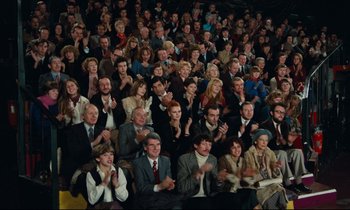Movie still from “My American Uncle” (1980), directed by Alain Resnais – A large group of people sitting in a room clapping and applauding; Wide shot, High angle