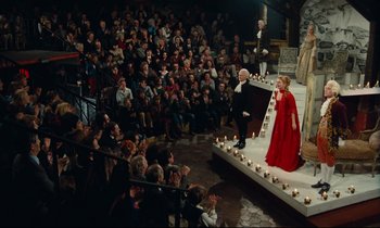 Movie still from “My American Uncle” (1980), directed by Alain Resnais – A crowd of people sitting and standing on a stage; Extreme Wide shot, High angle