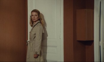 Movie still from “My American Uncle” (1980), directed by Alain Resnais – A woman standing in front of a white door; Medium shot, Over the shoulder angle