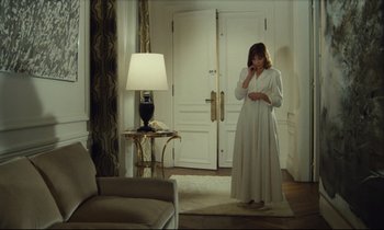 Movie still from “My American Uncle” (1980), directed by Alain Resnais – A woman in a white dress standing in front of a lamp; Wide shot, High angle