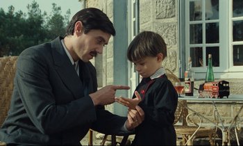 Movie still from “My American Uncle” (1980), directed by Alain Resnais – A man and a boy are playing a game together; Medium shot, Over the shoulder angle