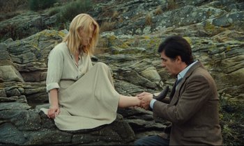 Movie still from “My American Uncle” (1980), directed by Alain Resnais – A man and a woman sitting on a rocky ground; Wide shot, High angle