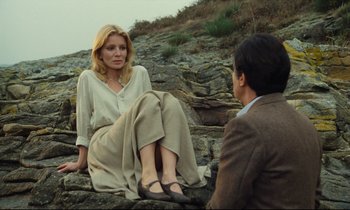 Movie still from “My American Uncle” (1980), directed by Alain Resnais – A woman sitting on the ground next to a man; Wide shot, Low angle