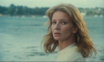 Movie still from “My American Uncle” (1980), directed by Alain Resnais – A woman in a white sweater standing in front of a body of water; Close Up shot, Low angle