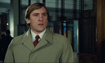 Movie still from “My American Uncle” (1980), directed by Alain Resnais – A man in a trench coat and a red tie; Close Up shot, Low angle