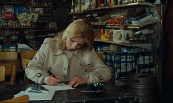 Movie still from “My American Uncle” (1980), directed by Alain Resnais – A woman sitting at a table writing on a piece of paper; Medium shot, High angle