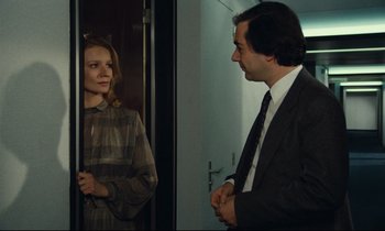 Movie still from “My American Uncle” (1980), directed by Alain Resnais – A man and a woman standing next to each other in a room; Medium shot, Over the shoulder angle