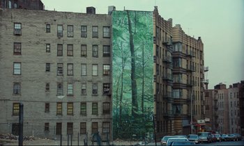 Movie still from “My American Uncle” (1980), directed by Alain Resnais – A large mural of a tree on the side of a building; Extreme Wide shot, Low angle