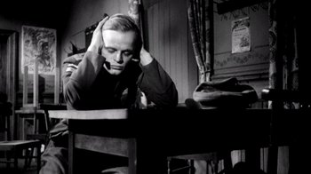 Movie still from “My Best Fiend” (1999), directed by Werner Herzog – A black and white photo of a man sitting at a table; Medium shot, High angle