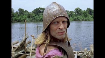 Movie still from “My Best Fiend” (1999), directed by Werner Herzog – A man wearing a helmet standing next to a body of water; Close Up shot, Low angle