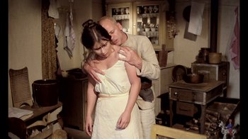 Movie still from “My Best Fiend” (1999), directed by Werner Herzog – A man and a woman embracing in a kitchen; Medium shot, Low angle