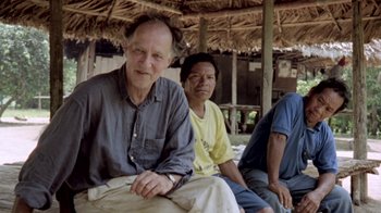 Movie still from “My Best Fiend” (1999), directed by Werner Herzog – A group of people sitting in front of a straw hut; Medium shot, Low angle