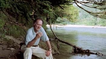 Movie still from “My Best Fiend” (1999), directed by Werner Herzog – An older man sitting on the shore of a river; Medium shot, Low angle