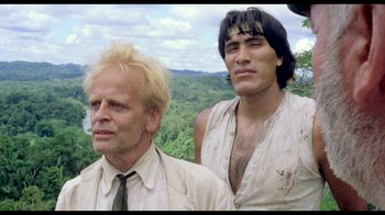 Movie still from “My Best Fiend” (1999), directed by Werner Herzog – Two men standing next to each other in front of a forest; Medium shot, Low angle