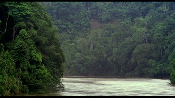 Movie still from “My Best Fiend” (1999), directed by Werner Herzog – A body of water surrounded by a forest of green trees; Extreme Wide shot, High angle