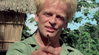 Movie still from “My Best Fiend” (1999), directed by Werner Herzog – A man with blonde hair holding a butterfly; Close Up shot, Low angle