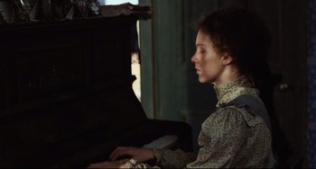 Movie still from “My Brilliant Career” (1979), directed by Gillian Armstrong – A woman sitting in front of an old piano; Medium shot, High angle
