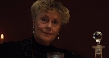 Movie still from “My Brilliant Career” (1979), directed by Gillian Armstrong – An older woman wearing a black dress and a pearl necklace; Close Up shot, Over the shoulder angle