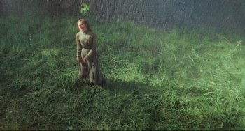 Movie still from “My Brilliant Career” (1979), directed by Gillian Armstrong – A woman standing in the grass in the rain; Wide shot, High angle