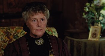An older woman wearing a black dress and a gold necklace