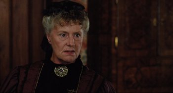 Movie still from “My Brilliant Career” (1979), directed by Gillian Armstrong – An older woman wearing a black hat and a black dress; Close Up shot, Over the shoulder angle