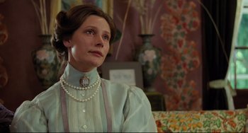 Movie still from “My Brilliant Career” (1979), directed by Gillian Armstrong – A woman wearing a dress and pearls sitting on a couch; Close Up shot, Low angle