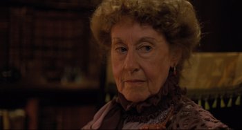 Movie still from “My Brilliant Career” (1979), directed by Gillian Armstrong – An older woman wearing a hat and looking at the camera; Close Up shot, Over the shoulder angle