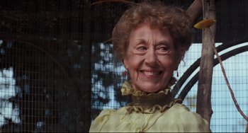 Movie still from “My Brilliant Career” (1979), directed by Gillian Armstrong – An older woman wearing a yellow dress smiling for the camera; Close Up shot, Low angle