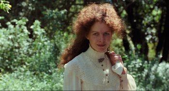 Movie still from “My Brilliant Career” (1979), directed by Gillian Armstrong – A woman with long red curly hair holding a remote control; Close Up shot, Low angle