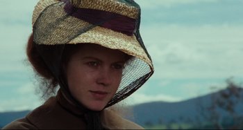 Movie still from “My Brilliant Career” (1979), directed by Gillian Armstrong – A woman wearing a straw hat and a brown coat; Close Up shot, Low angle