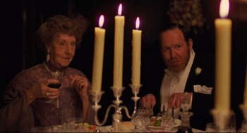 Movie still from “My Brilliant Career” (1979), directed by Gillian Armstrong – A man and a woman sitting at a dinner table with lit candles; Medium shot, Over the shoulder angle