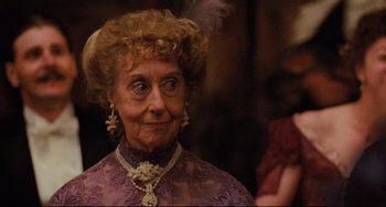 Movie still from “My Brilliant Career” (1979), directed by Gillian Armstrong – An older woman wearing a purple dress and a necklace; Close Up shot, Over the shoulder angle