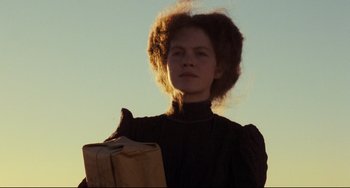 Movie still from “My Brilliant Career” (1979), directed by Gillian Armstrong – A woman holding a paper bag while standing in the sunlight; Close Up shot, Low angle