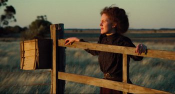 Movie still from “My Brilliant Career” (1979), directed by Gillian Armstrong – A woman leaning on a wooden fence in a field; Medium shot, Low angle