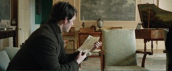 Movie still from “My Cousin Rachel” (2017), directed by Roger Michell – A man holding a piece of paper while sitting in a chair; Medium shot, Over the shoulder angle