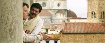 Movie still from “My Cousin Rachel” (2017), directed by Roger Michell – A man holding a piece of paper in front of a building; Medium shot, Low angle