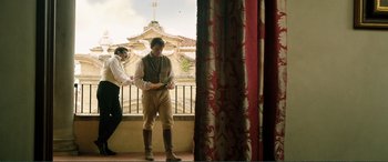 Movie still from “My Cousin Rachel” (2017), directed by Roger Michell – A man standing in front of a window wearing a vest and boots; Wide shot, Low angle