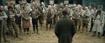 Movie still from “My Cousin Rachel” (2017), directed by Roger Michell – A group of men standing in a field with a man in the foreground; Wide shot, Over the shoulder angle