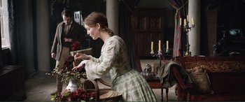 Movie still from “My Cousin Rachel” (2017), directed by Roger Michell – A woman in a green floral dress standing in front of a table; Medium shot, Over the shoulder angle