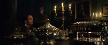 Movie still from “My Cousin Rachel” (2017), directed by Roger Michell – Two people sitting at a dinner table with candles lit; Medium shot, Over the shoulder angle