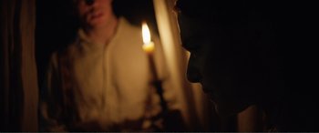 Movie still from “My Cousin Rachel” (2017), directed by Roger Michell – A candle is lit in the middle of a man's face; Close Up shot, Over the shoulder angle