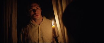 Movie still from “My Cousin Rachel” (2017), directed by Roger Michell – A man standing in front of a window holding a lit candle; Close Up shot, Low angle