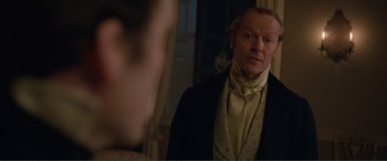 Movie still from “My Cousin Rachel” (2017), directed by Roger Michell – A man in a suit and tie standing in front of a mirror; Close Up shot, Over the shoulder angle