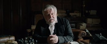 Movie still from “My Cousin Rachel” (2017), directed by Roger Michell – An older man sitting at a table in front of a window; Close Up shot, Over the shoulder angle