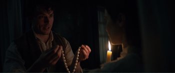 Movie still from “My Cousin Rachel” (2017), directed by Roger Michell – A woman holding a string of pearls in front of a lit candle; Close Up shot, Over the shoulder angle