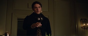 Movie still from “My Cousin Rachel” (2017), directed by Roger Michell – A man holding a glass of wine in his hand; Medium shot, Over the shoulder angle