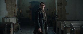 Movie still from “My Cousin Rachel” (2017), directed by Roger Michell – A man standing in a dark room holding a hat; Medium shot, Low angle